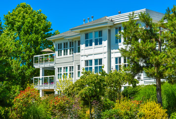 Top of luxury apartment building with green trees in front.