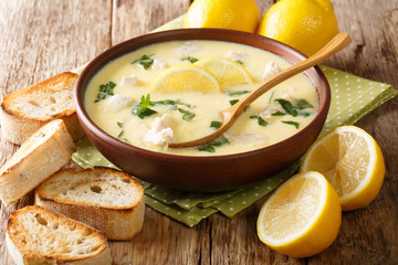 Classic Mediterranean lemon soup with chicken close-up in a bowl with bread. horizontal