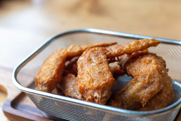 Close up crispy delicious hot Fried chicken wings in basket on wooden table.