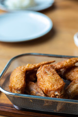 Close up crispy delicious hot Fried chicken wings in basket on wooden table.