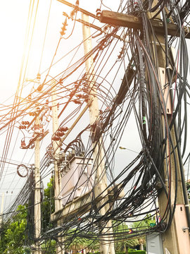 The chaos of cables and wires on an electric pole.Messy wires attached to  the electric mast. Many electrical cable in Bangkok, Thailand, concept of  electricity. Photos | Adobe Stock