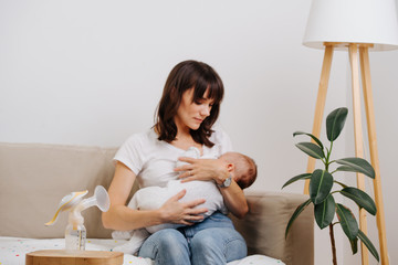 Caucasian mother is decently breastfeeding her baby, without exposing herself.