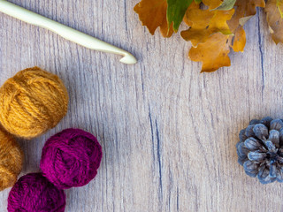 Autumn crochet image with fall leaves, crochet hook, balls of wool, pine cone. Top view with copy space. 