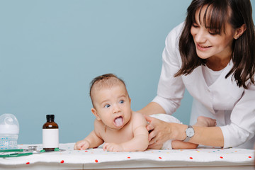 Doctor massaging infant baby on a special table over blue background