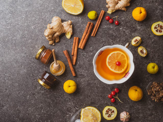 green tea with lemon,red berries, different honey,ginger, propolis, cinnamon sticks, cydonia, Warm drink beverage infusion in white cup for cold flu winter fall days
