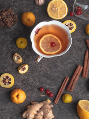 green tea with lemon,red berries, different honey,ginger, propolis, cinnamon sticks, cydonia, Warm drink beverage infusion in white cup for cold flu winter fall days