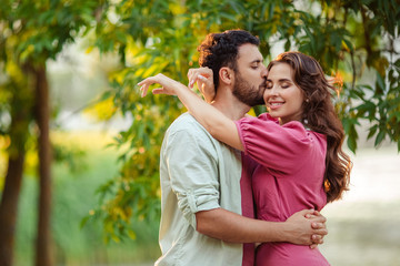 Fototapeta premium Beautiful young couple man and woman in love with each other hug and kiss on nature in the summer.