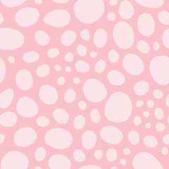 Hand drawn pink circles and oval silhouette shapes in a tossed abstract seamless pattern. Vector design background design.