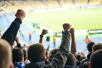 Football- soccer fans support their team and celebrate goal in full stadium with open air.