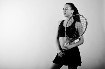 Black and white portrait of beautiful young woman player in sports clothes holding tennis racket...
