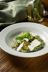 Green Gnocchi with basil, spinach, pesto feta cheese in composition with green cloth and olive oil. Close up, selective focus. Traditional italian cuisine.