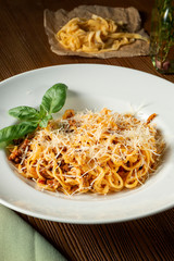 Bolognese pasta with red sauce, parmesan and minced meat. Italian spaghetti with meat in a white plate on a wooden background.