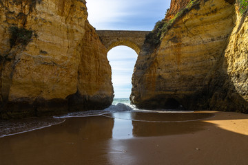 The scenic Roman bridge in Lagos connecting the cliffs over the beach, Algarve, Portugal