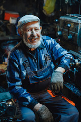 Senior elderly male turner handles metal on machine. Concept pension worker industrial, workplace
