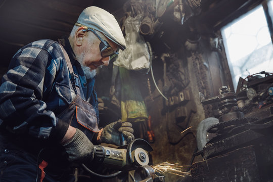 Senior elderly male turner handles metal on machine. Concept pension worker industrial, workplace