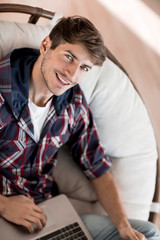 attractive guy is typing on his laptop.