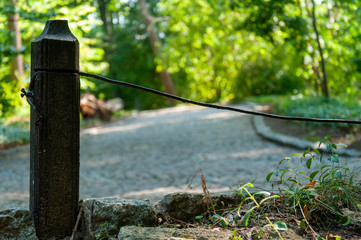 The road in the park. Green background. Metal post close-up on the background of the road and green park.
