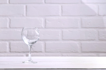 Broken wine glass on a white wooden table against the background of a loft. Broken, old dishes.