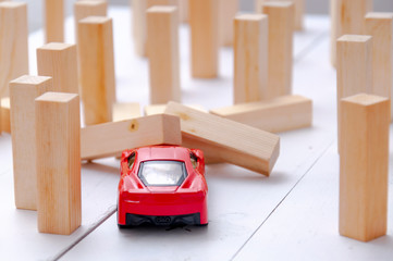 The red toy car overcomes all obstacles in the way and barriers reaching the goal and knocking down obstacles in its path. A red car rides and knocks down wooden poles in its path.