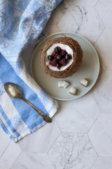 Berry dessert with yogurt in a cup of coconut on a light background. Blackberries, raspberries, blueberries, black currants. Blue napkin