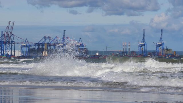 Container Terminal Cranes on Baltic Sea with Heavy Waves Splashing into Shore