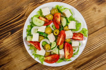 Greek salad with fresh vegetables, feta cheese and green olives on wooden table. Top view