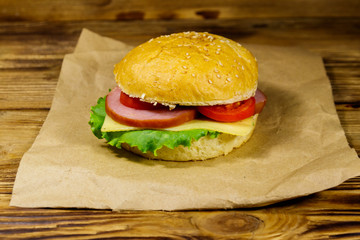 Fresh delicious homemade cheeseburger on brown paper on wooden table
