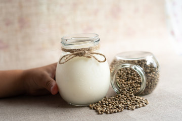 children hand hold vegan fresh milk from hemp seeds in a glass jar , clean eating, non-dairy milk
