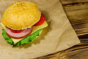 Fresh delicious homemade cheeseburger on brown paper on wooden table