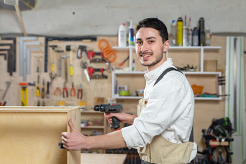 Naklejka na ściany i meble furniture factory, Small-Sized Companies and people concept - Young worker works in a factory for the production of furniture