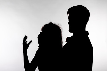 Domestic violence and abuse concept - Silhouette of man beating defenseless woman