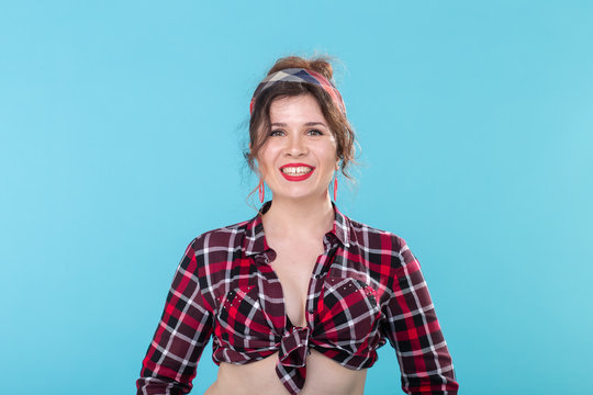 Positive beautiful young woman in a plaid vintage shirt looking at the camera and smiling posing on a blue background
