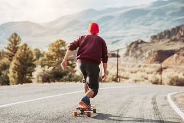 Man skateboarding at mountain road - obrazy, fototapety, plakaty