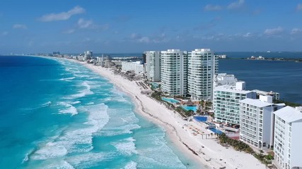 Aerial shot of the hotel zone in cancún, in a sunny day hitting the blue waters of the caribbean. Revealing the whole line of hotels going up.