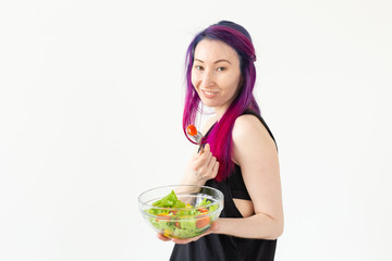 Young asian fitness girl with colored hair holding in hands vegetable salad. Healthy eating concept.