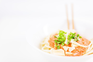 Italian pasta with chopsticks, tomato sauce, parmesan cheese, fresh oregano and basil - on white background.