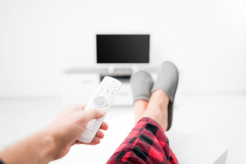 Man looking at TV with legs on the table in living room.