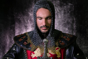 Portrait of handsome medieval knight in suit of armour with beard looking down in contemplation