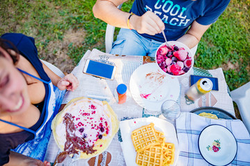 People making a picnic with sweet waffle and pancaces in the garden.