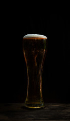 Glass of beer with foam on dark background