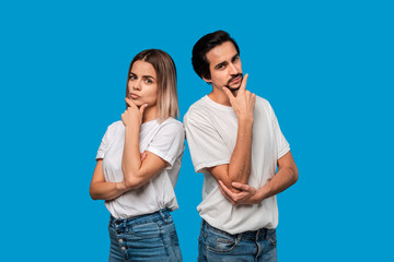 Naklejka premium Thoughtful bearded brunet man with mustache and blond woman in white t-shirts and blue jeands standing isolated over white background. Concept of conversation and thinking.