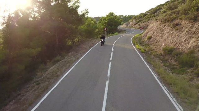 Video of motorcyclist driving his motorbike on the mountain road in the country side. Aerial view.