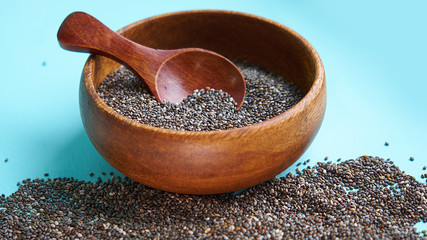 Nutritious chia seeds on a blue background. chia seeds in bowl and a spoon on kitchen table top...