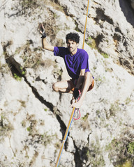 A man is walking along a stretched sling. Highline in the mountains. Man catches balance....