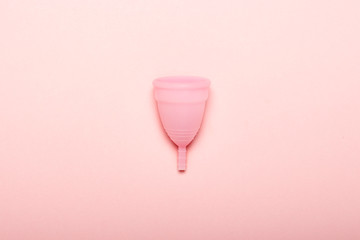 Menstrual cup on a pink background. The concept of menstruation. Flat lay, top
