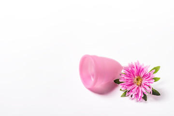 Pink menstrual cup and flower on a white background. Concept of menstruation, the choice between feminine hygiene products. Flat lay, top