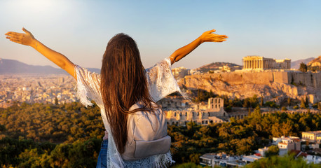 Glückliche Touristin mit ausgestreckten Armen genießt den Ausblick auf die Akropolis von Athen, Griechenland, bei einem Sommer Sonnenuntergang