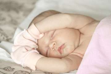 close up portrait of a sleeping naked newborn baby girl on a white blanket