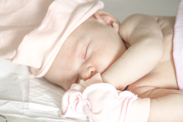 Fototapeta na wymiar close up portrait of a sleeping naked newborn baby girl on a white blanket