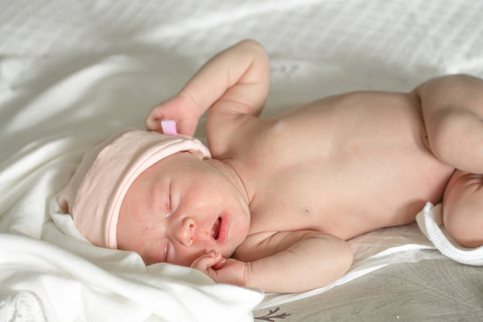 close up portrait of a sleeping naked newborn baby girl on a white blanket